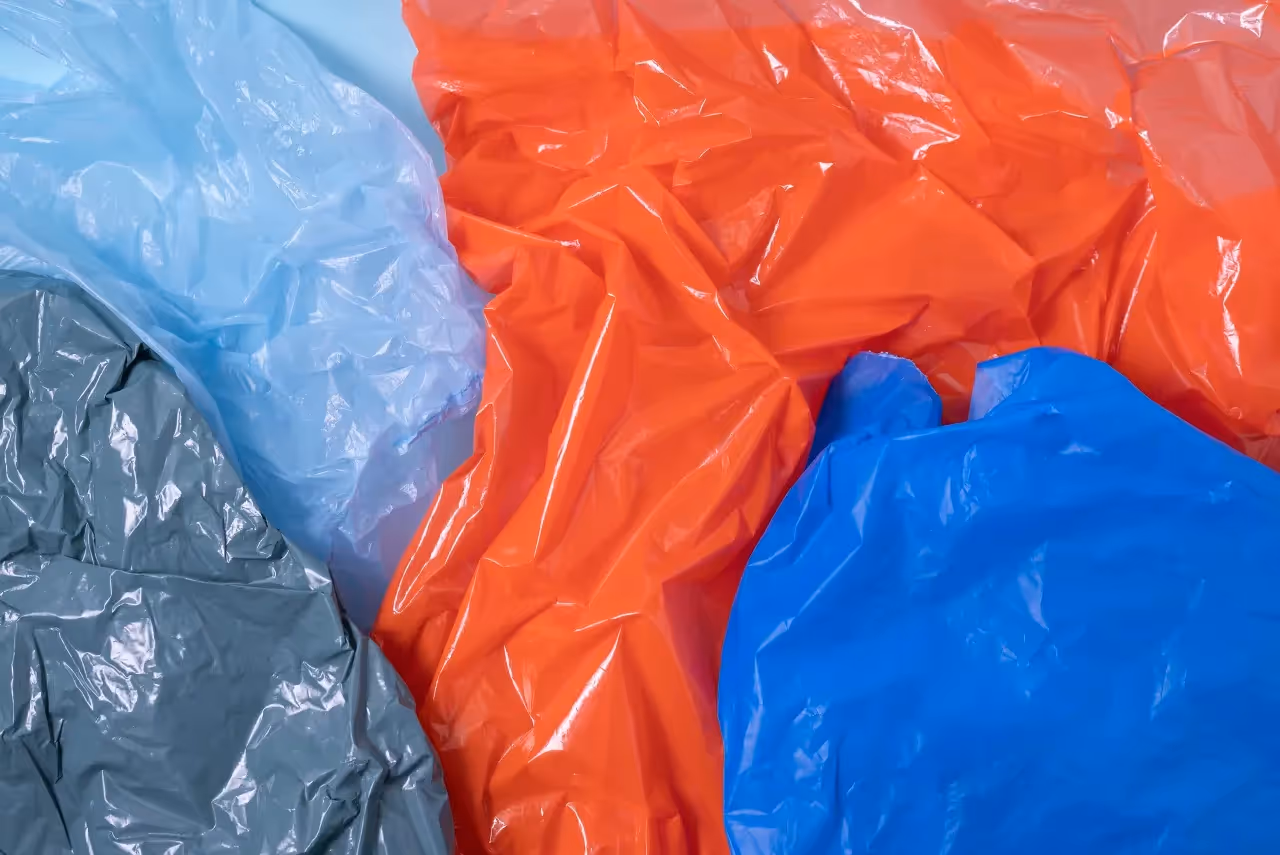 A pile of colorful, crinkled plastic bags, representing post-consumer plastic film waste ready for recycling.