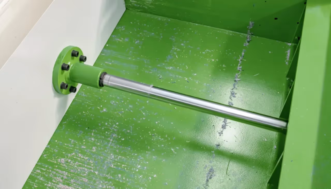 Hydraulic pusher assembly that stabilizes feeding into a shredder rotor.